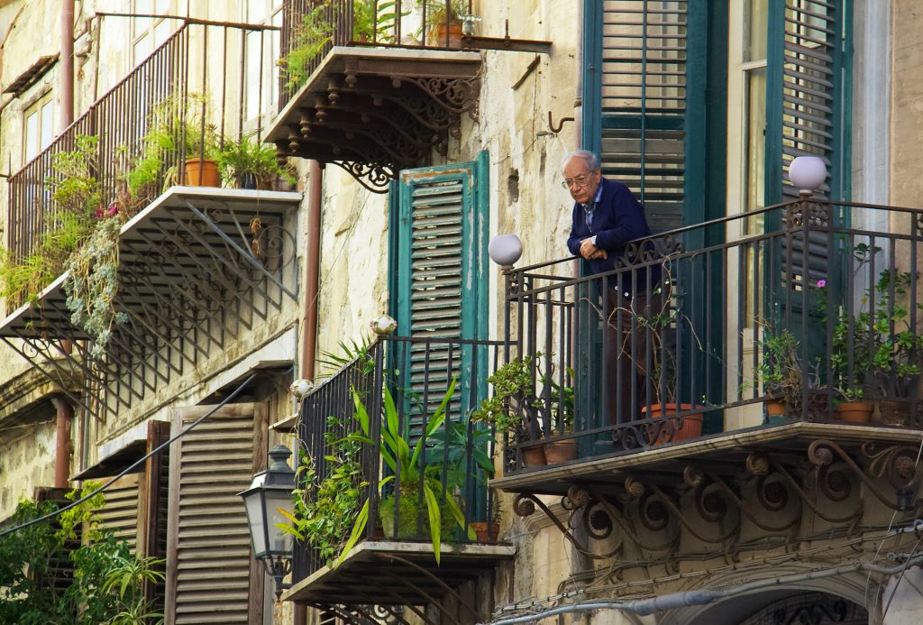 old man looking out balcony apartment