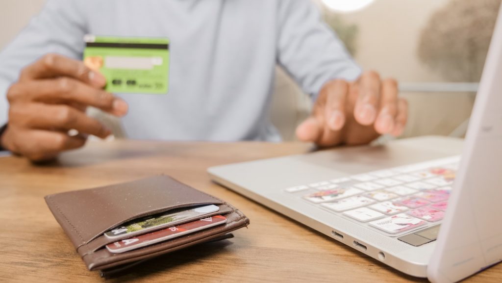 black man holding credit card using laptop