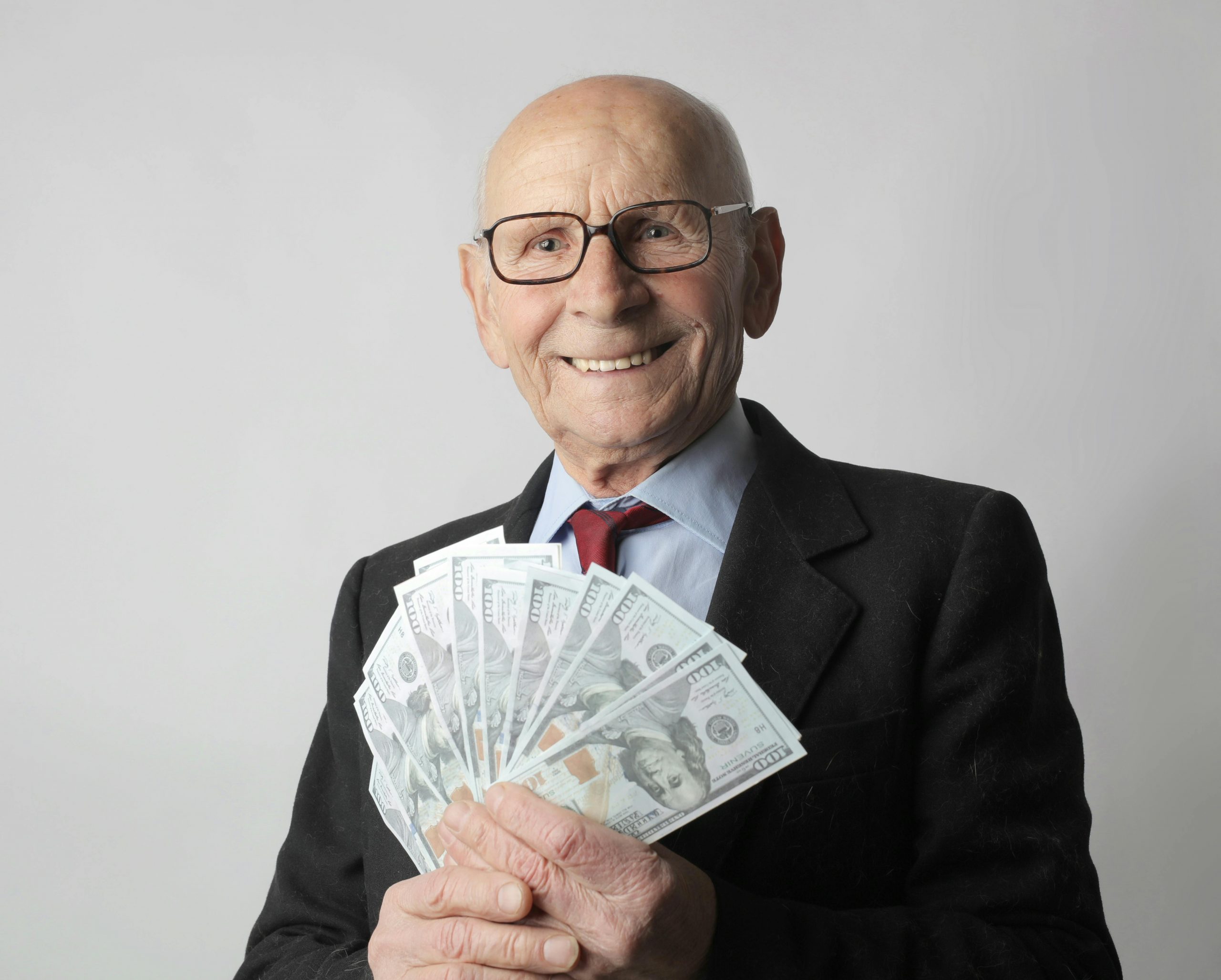 senior man holding a fan of dollar bills